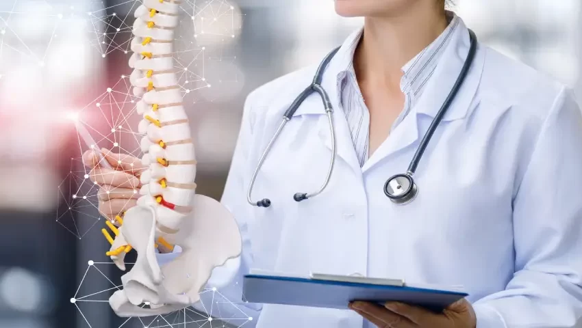 Orthopedic doctor holding spine model to explain spine and joint conditions.
